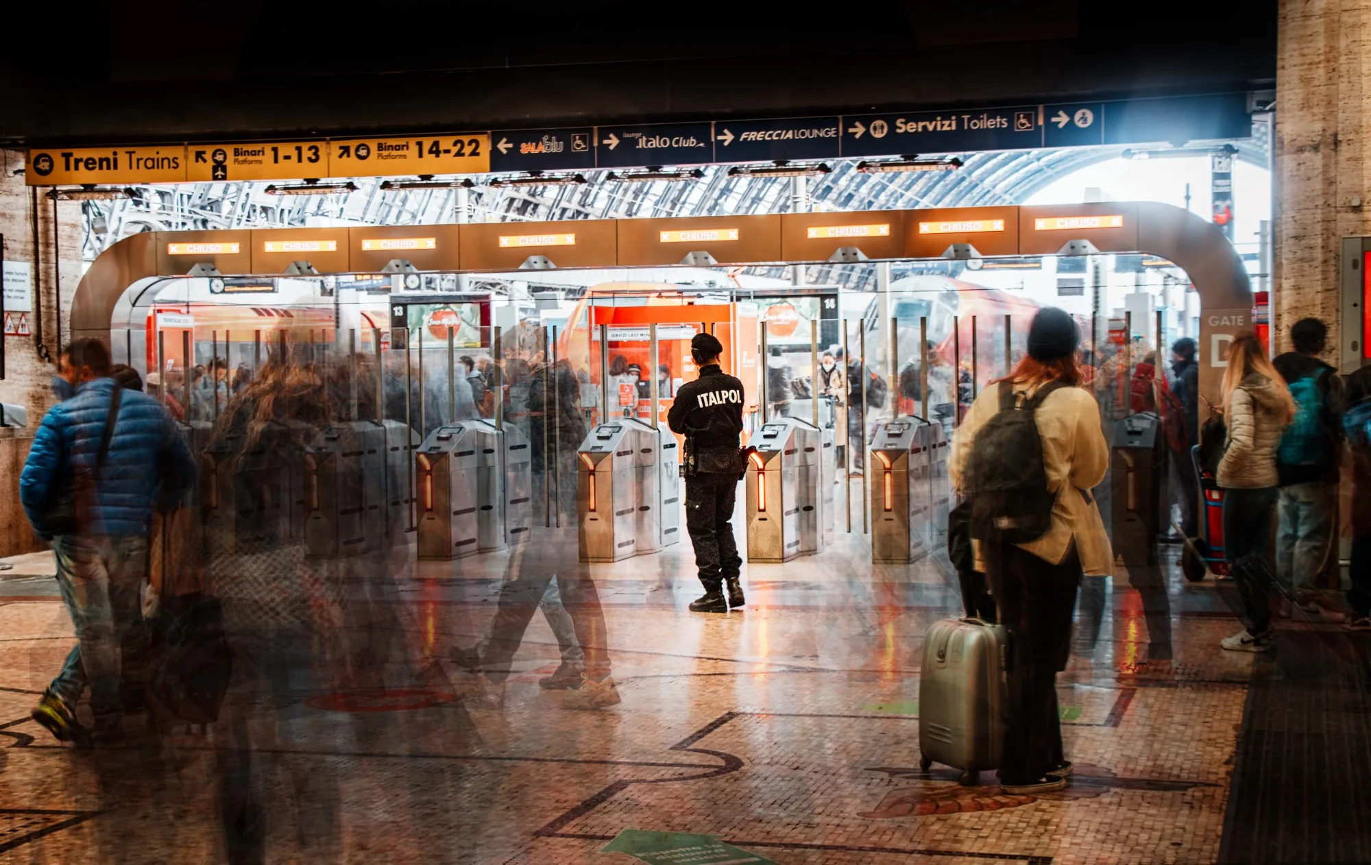 A stationary figure surrounded by moving travelers at Milano station